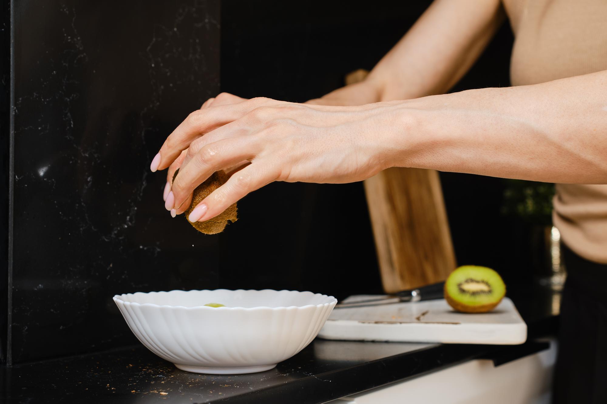 Hands seasoning a protein over a clean stainless counter